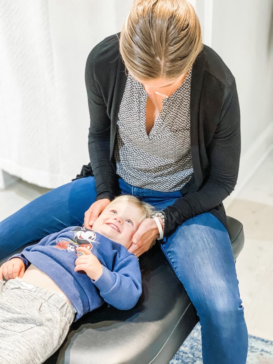 Dr. Amanda giving a smiling toddler a gentle upper cervical adjustment at Limitless Chiropractic in Ballantyne