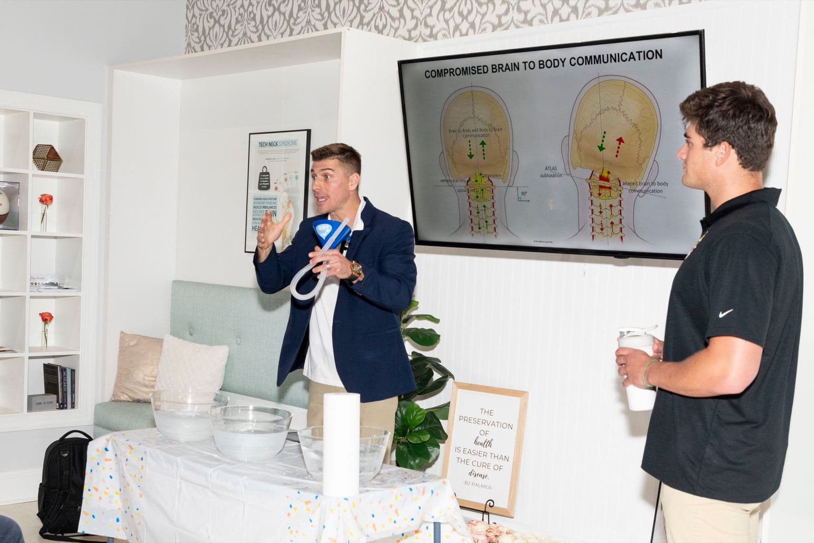 Dr. Tim Hartman demonstrating beside a slide titled Compromised Brain to Body Communication
