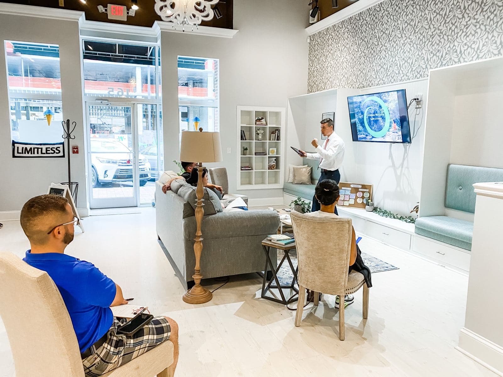 A small group seated on couches and chairs in the Limitless Chiropractic lounge watching a presentation