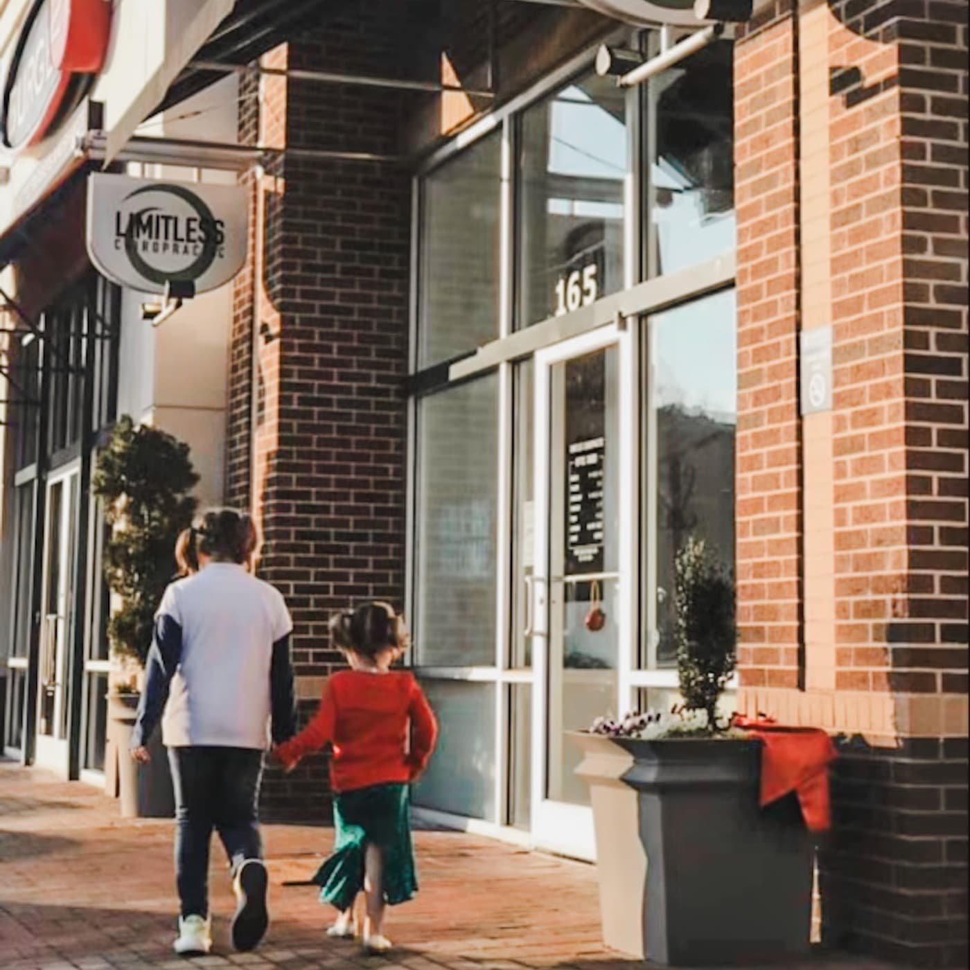 A mom and child walking up to the Limitless Chiropractic front door in Ballantyne Village, Charlotte NC